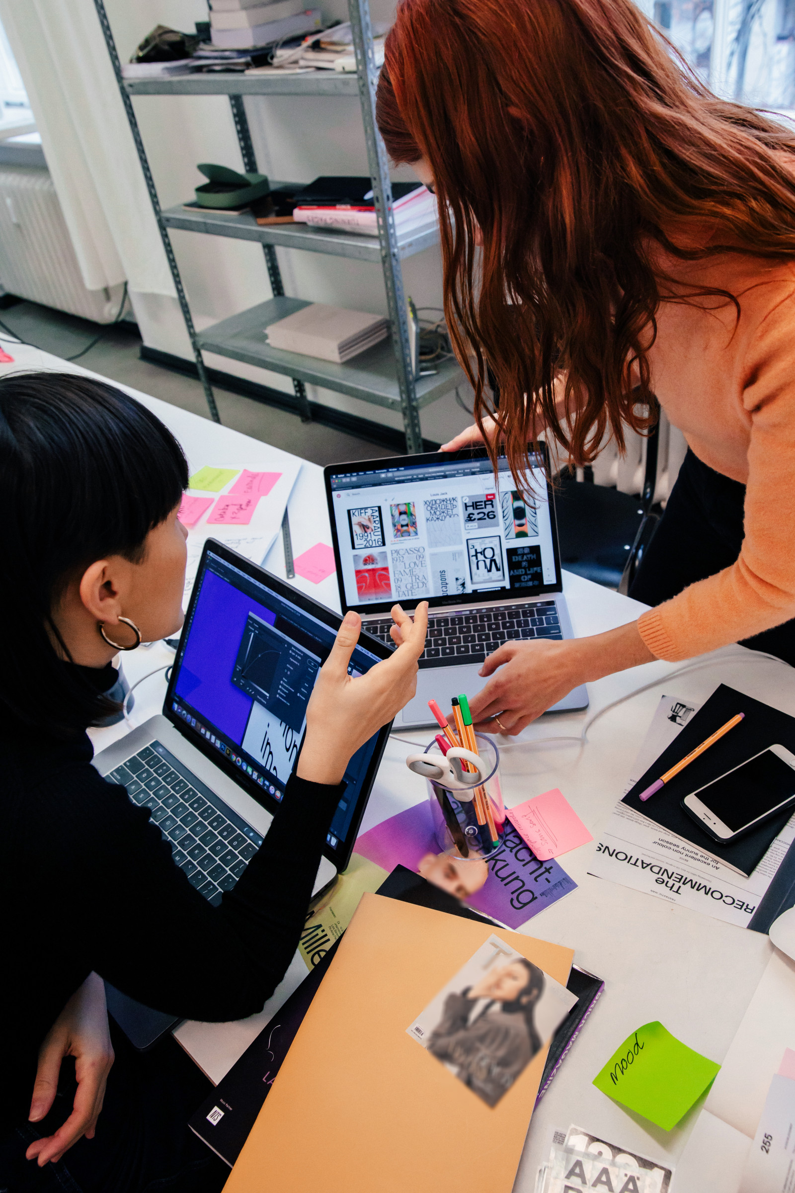 A team collaborating around a table with laptops and research materials